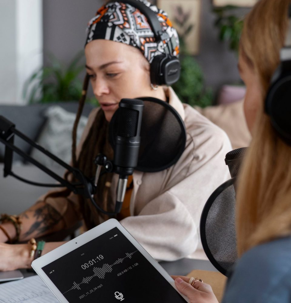 Two people record a radio segment with microphones in a studio
